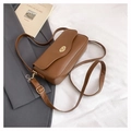 Close-up of caramel leather crossbody bag with golden twist lock on a grey suit background - Brown