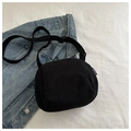Detalle del bolso bandolera de pana negra con etiqueta de logo sobre fondo denim - Negro