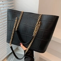 Black crocodile embossed leather tote bag with gold chain straps shown with lifestyle model - Black