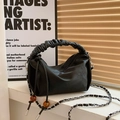Schwarze Falten-Handtasche mit Kettenträger und Bernstein-Perle in schickem Studio - Schwarz