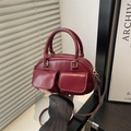 Minimalistische bordeauxrode Boston handtas met klepzakken en handvatten in stadslicht - Rood