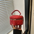 Detail of red quilted mini bag featuring golden dual zippers and woven chain strap - Red
