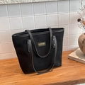 Bolso tote negro de ante con asas de cuero y remaches dorados sobre mesa de madera - Negro
