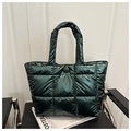 Dettaglio borsa shopper trapuntata verde scuro lucida su una sedia dal design moderno - Verde
