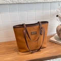 Bolso tote de ante marrón con correas en contraste sobre un estante de madera acogedor - Marrón