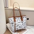 Dettaglio della borsa tote con stampa graffiti, manici in pelle marrone e motivi - Marrone