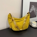 Detail of ginger yellow nylon dumpling bag with adjustable strap on a modern desk - Yellow
