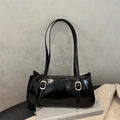 Close-up of black glossy leather underarm bag with gold buckles in a minimalist setting - Black