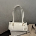 Detail of cream white retro baguette bag showing glossy leather and gold buckle accents - White