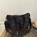 Détail de l'imprimé cerises et des poches zippées fonctionnelles sur sac à bandoulière - Noir