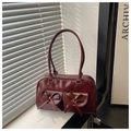 Dettaglio borsa in vernice bordeaux con tasche con fiocco sul davanzale della finestra - Rosso