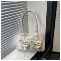 Dettaglio della borsa a tracolla bianco avorio lucida con fiocchi decorativi simmetrici - Bianco
