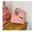 Detail van roze pluizige minitas met konijnenhanger en Cutie-borduurwerk op houten tafel - Roze