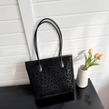 Detail view of large leopard print tote bag with leather straps on a modern display - Black
