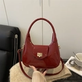 Elegante bolso de charol granate con cierre dorado sobre un fondo de punto suave - Rojo