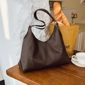 Detail einer großen braunen Vintage-Hobo-Tasche neben Kaffee und Brot im Café-Stil - Braun