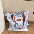 Dettaglio della borsa tote in tela blu con stampa ciliegia e manici in ecopelle - Blu