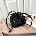 Fashionable black sequin drawstring bucket bag on stylish beige trench coat background - Black