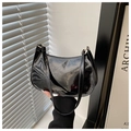 Detail of a chic black patent leather baguette bag featuring a glossy mirror finish texture - Black