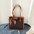 Close-up of a printed tote bag with NK monogram and a brown silk scarf on a denim jacket - Brown
