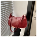 Close-up of a glossy red patent leather baguette bag with zip closure and shoulder strap - Red