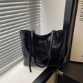 Minimalist glossy black tote bag with long straps in a stylish lifestyle setting - Black