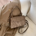 Metallic bronze pleated crossbody bag with dual top handles on a khaki trench coat - Brown