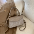 Detailed close-up of velvet textured handbag with unique knot handle and gold hardware - Khaki