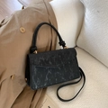 Detail of black marble texture handbag with gold hardware on a white sofa scene - Black
