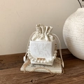 Detail of cream bucket bag with elegant pearl handle and gold chain on wooden table - White
