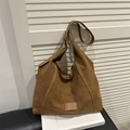 Bolso tote marrón de ante mate de gran capacidad sobre fondo de persiana blanca - Marrón