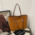 Bolso tote marrón con lazo dorado sobre maleta blanca en una escena de estilo de vida - Marrón
