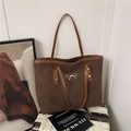 Bolso tote marrón oscuro mate con detalle de lazo dorado sobre maleta blanca - Marrón