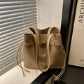 Beige bucket bag with gold buckle and side tassels on window sill with natural light - Khaki