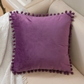 Deep purple velvet pillow case with pom-pom edges on a cozy sofa corner - Purple