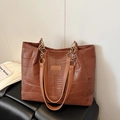 Close-up of brown crocodile texture leather tote bag with elegant gold chain handle detail - Tan