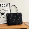 Close-up of black tote bag featuring white bow patterns and gold metallic hardware details - Black