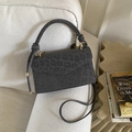 Detail der grauen Handtasche mit Leopardenmuster und goldenen Beschlägen auf Sofa - Grau