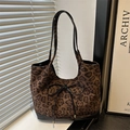 Große Shopper-Tasche mit Leopardenmuster, Lederriemen und Schleife auf einem Tisch - Schwarz
