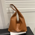 Sac hobo en cuir souple marron pour femme avec large bandoulière sur un livre blanc - Marron