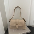 Detail der glänzenden beige Schultertasche mit goldener Metallschnalle auf schlichtem Grund - Khaki