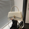 Elegant white structured handbag with a golden twist lock and curved base, held by hand - White