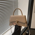 Elegant apricot faux leather crossbody handbag with golden metal lock shown in lifestyle set - Khaki