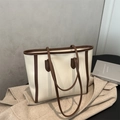 Detalle de bolso tote blanco roto con ribete marrón sobre abrigo beige elegante - Blanco