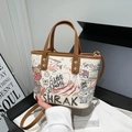 White graffiti tote bag with colorful bear prints and brown leather trim accents - White
