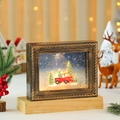 Detalle de marco navideño vintage con escena de nieve luminosa sobre base de madera - Estilo Coche