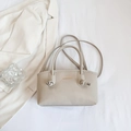 Detailaufnahme einer beigen Kunstleder-Handtasche mit goldener Fashion & Bags Aufschrift - Weiß