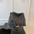 Detail van de donkere denim textuur en de metalen kettingriem van de grote draagtas - Zwart