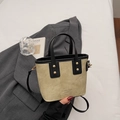 Bolso cubo beige con asa de cuero negro y tachuelas doradas en un entorno lifestyle - Blanco y Negro
