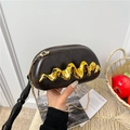Sac bandoulière ovale en cuir marron avec boucle dorée ondulée sur tapis tressé - Marron